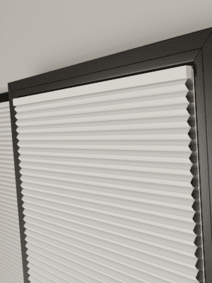 This image shows white clic honey comb blinds fitted onto a black window frame