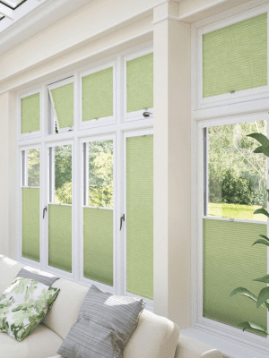 This image shows light green perfect-fit blinds attached to white window frames. SOme are open and some are closed.