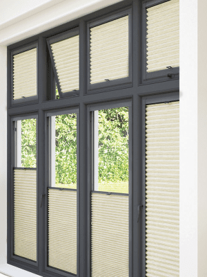 This image shows sand coloured perfect-fit honeycomb blinds, half up and half down, fitted onto black window frames.